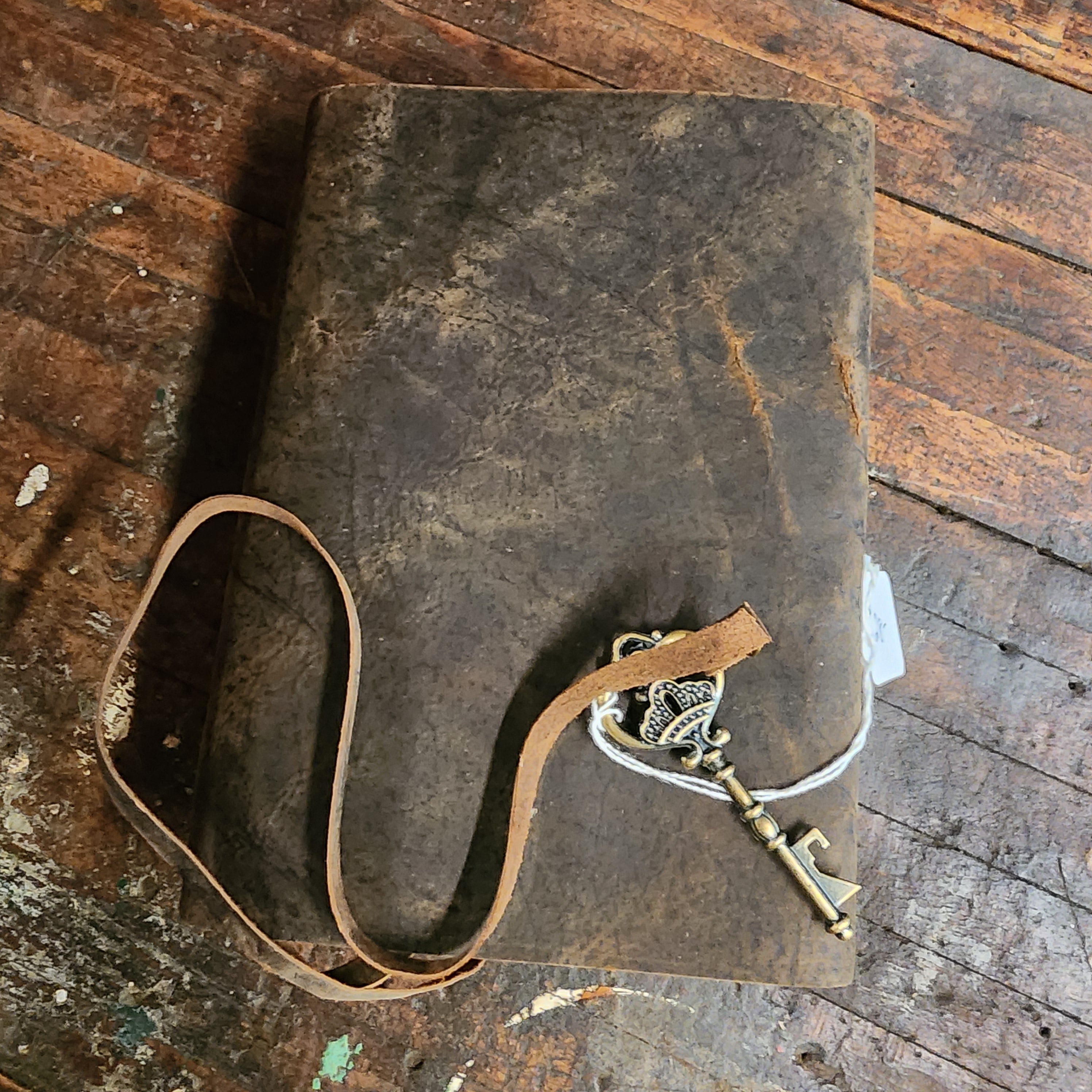 Distressed walnut leather journal closed beside books | The Olde 1840